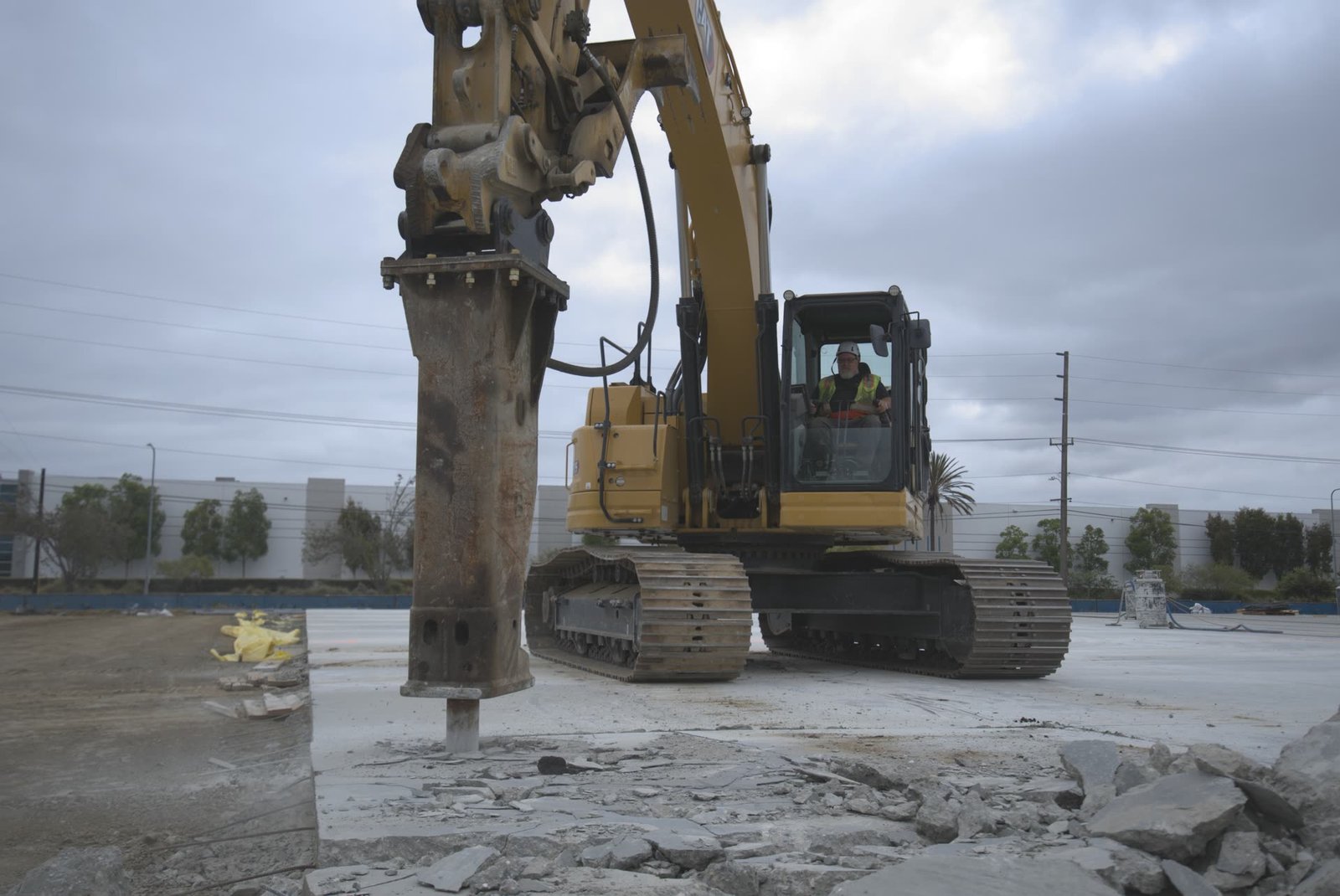 Silhouette of excavator-mounted hydraulic breaker against blue dusk sky