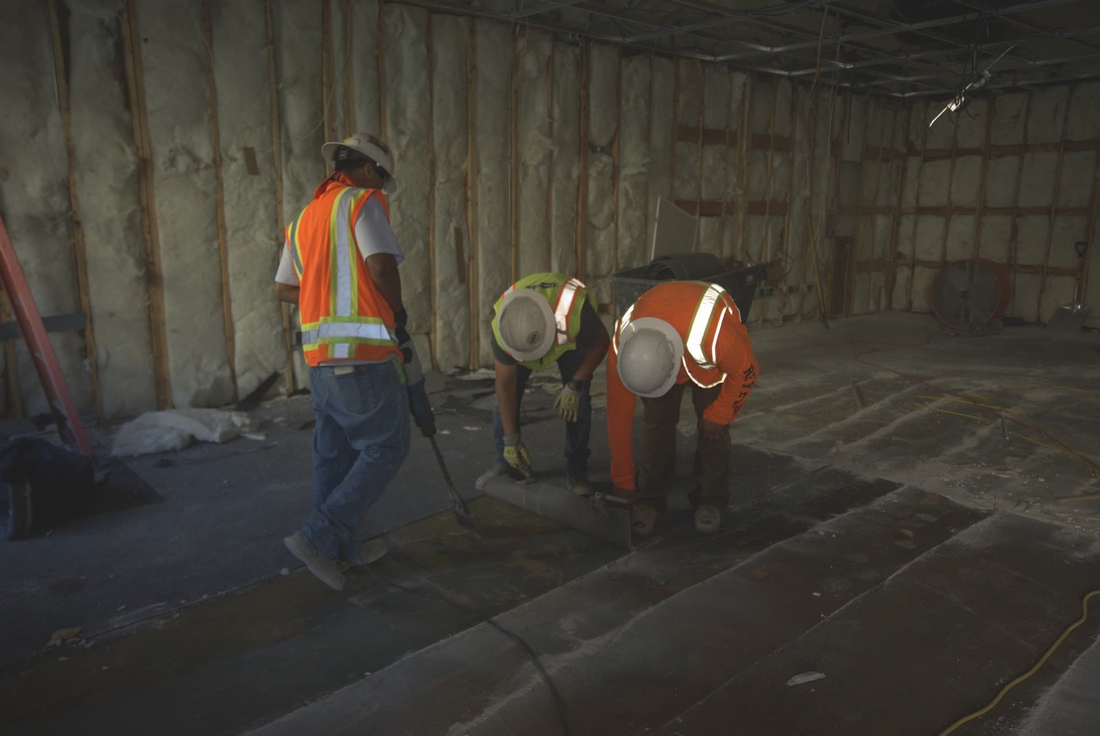 DSI crew actively working with pneumatic tools to break concrete inside stripped commercial building