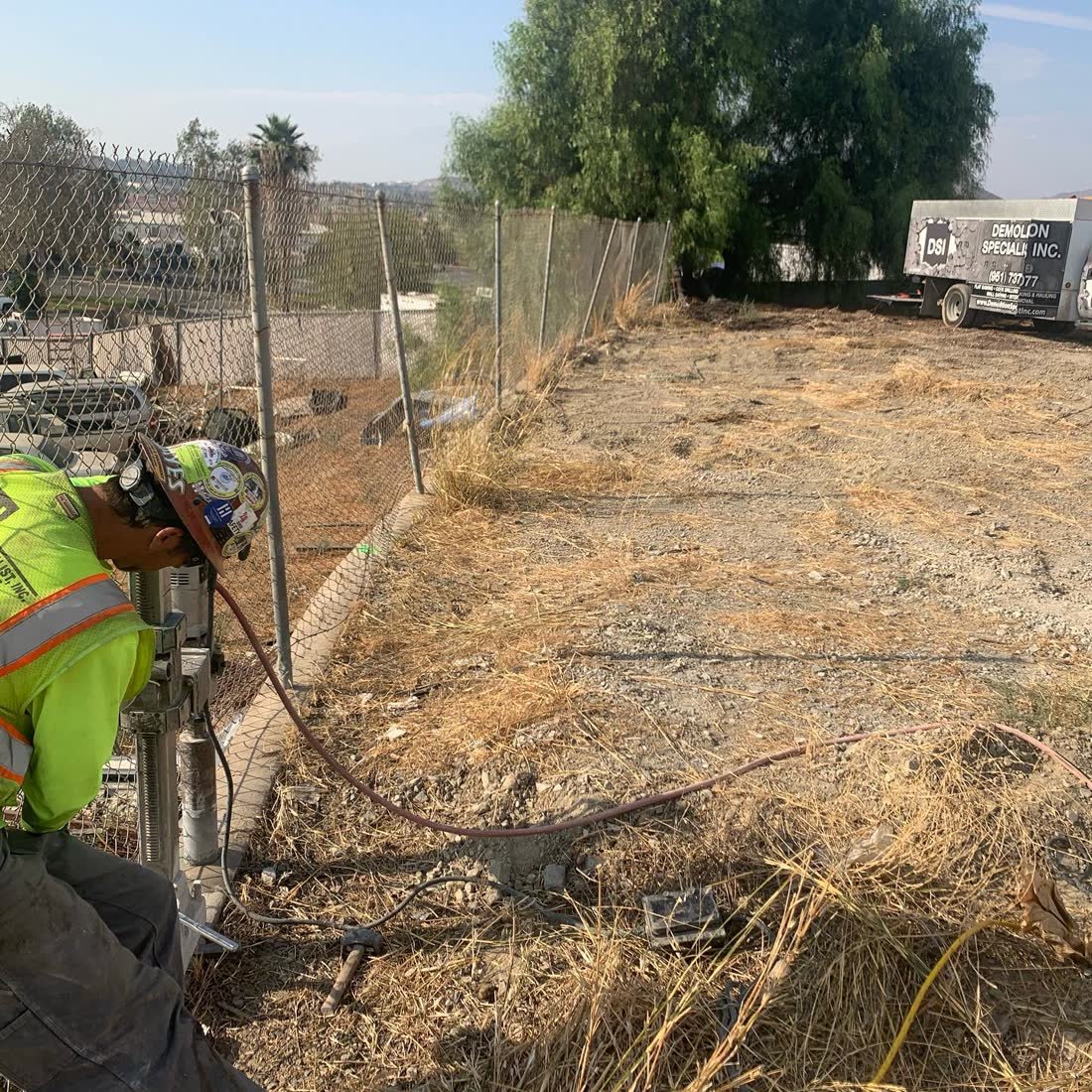 DSI operator running handheld core drill on concrete with DSI service truck in background