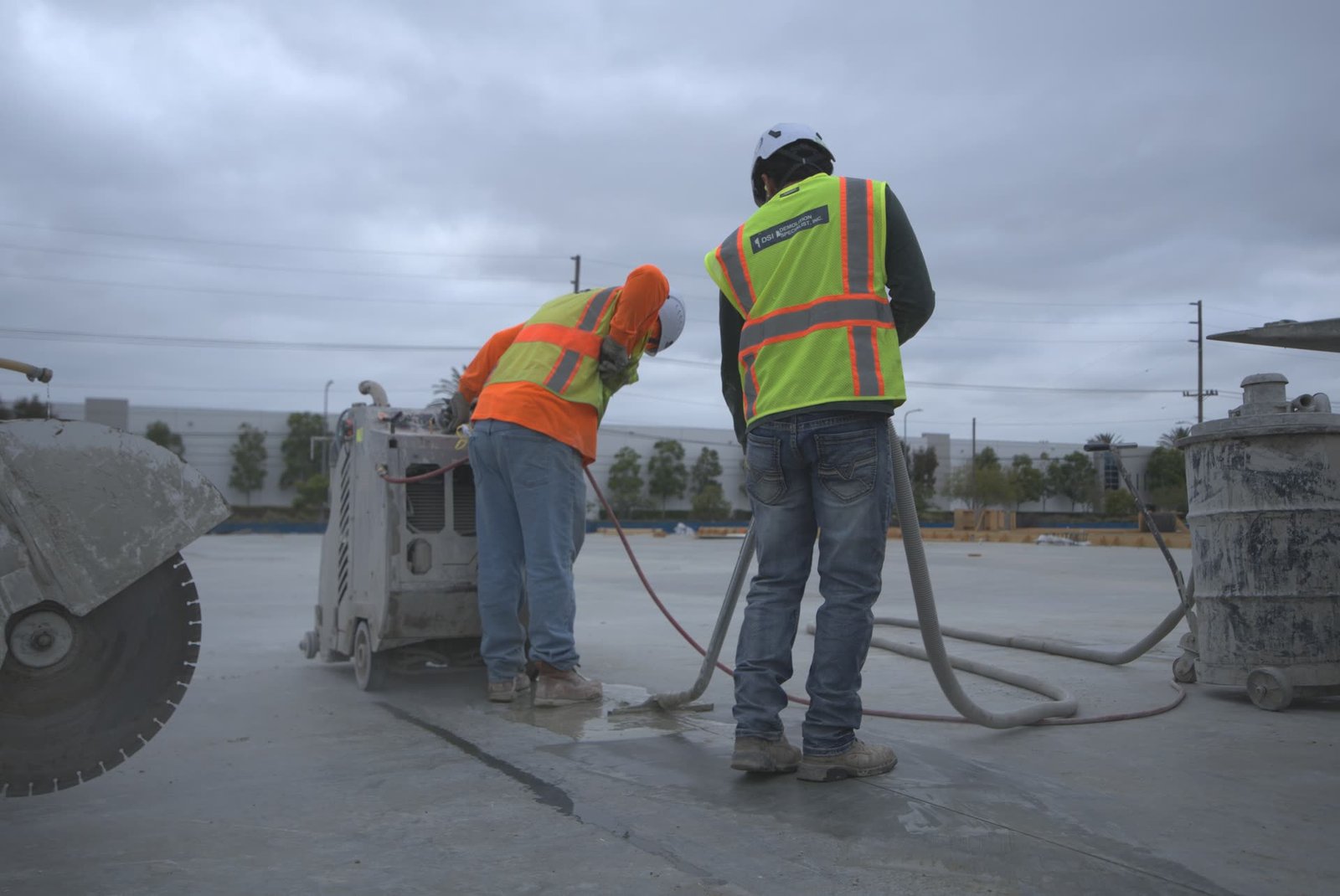 DSI crew member flat sawing concrete slab with walk-behind diamond blade saw — DSI truck prominently in background