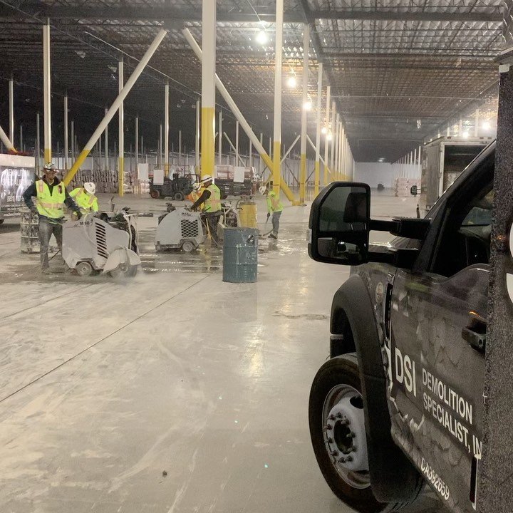 DSI flat sawing crew with multiple ride-on saws cutting warehouse floor — DSI service truck in foreground