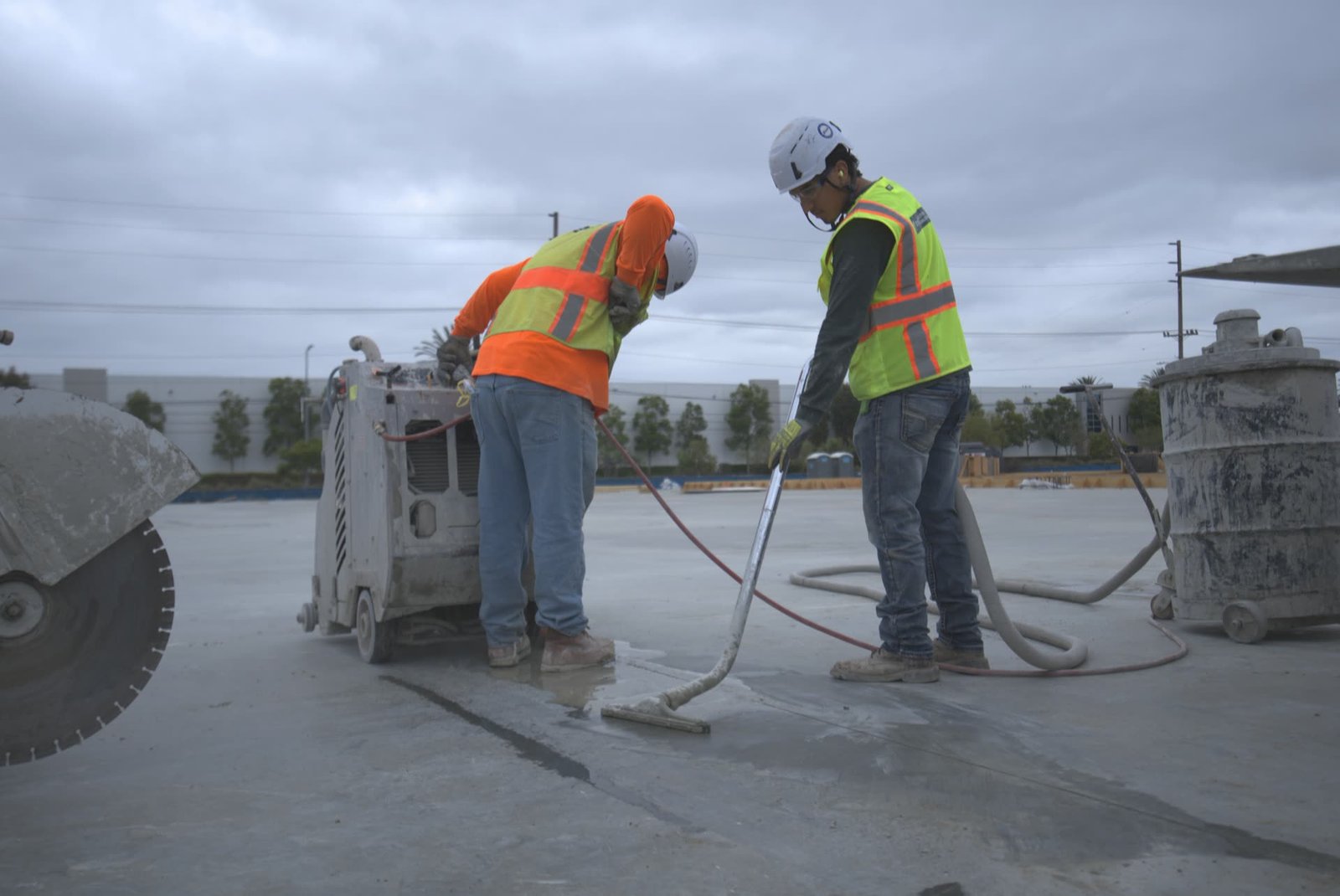 Worker hand sawing concrete with diamond blade walk-behind saw on commercial job site