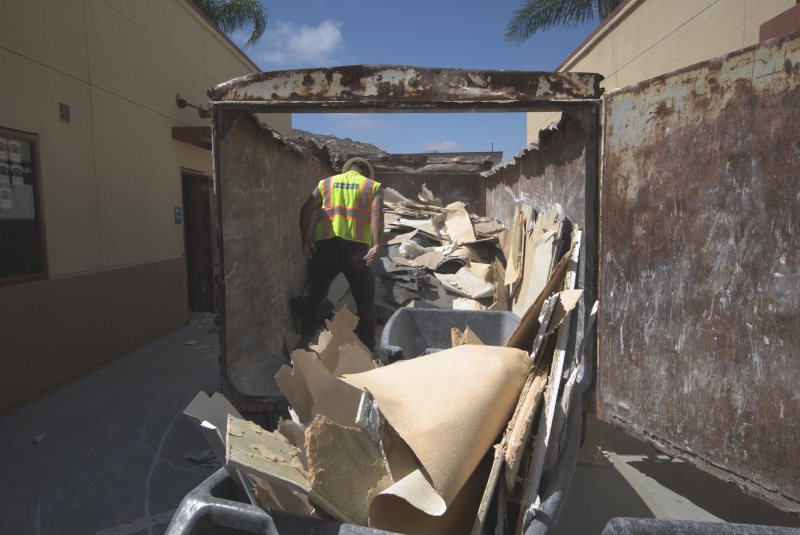 Construction debris being loaded into roll-off bin during commercial interior demolition